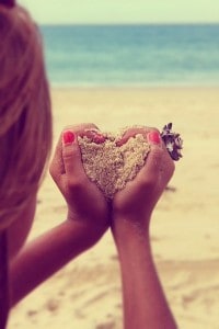 hands holding sand in a heart shape